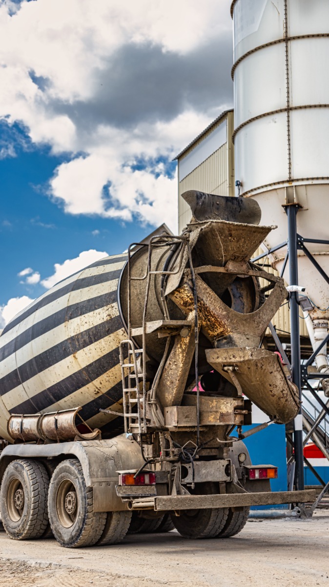 Concrete mixer truck in front of a concrete batching plant, cement factory. Loading concrete mixer truck. Close-up. Delivery of concrete to the construction site. Monolithic concrete works.